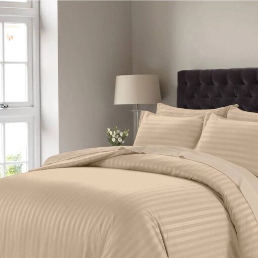 طقم مفرش سرير مخطط بلون بيج مع لحاف سرير أغطية وسائد متناسقة على سرير مع لوح أمامي منجد داكن اللون في غرفة نوم عصرية.