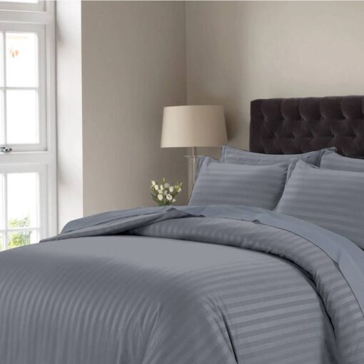 Dark gray striped comforter set with matching pillow shams on a bed with a dark tufted headboard in a modern bedroom setting.