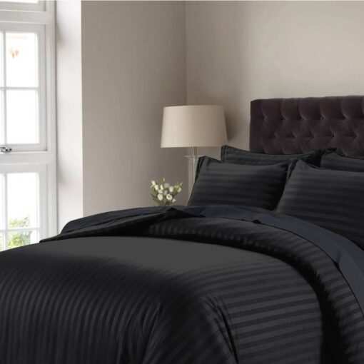 Black striped comforter set with matching pillow shams on a bed with a dark tufted headboard in a modern bedroom setting.