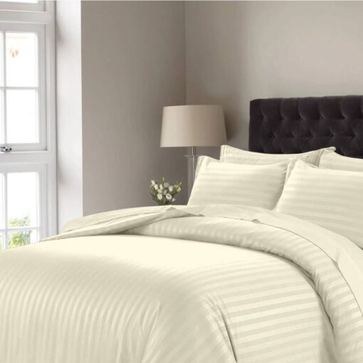 Off white striped comforter set with matching pillow shams on a bed with a dark tufted headboard in a modern bedroom setting.