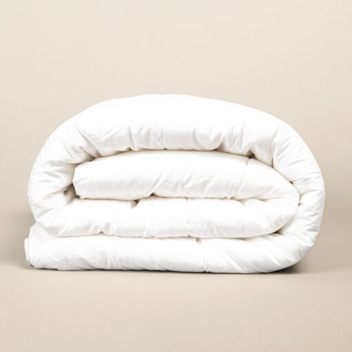 Folded white duvet made of soft microfiber fabric, neatly stacked on a neutral beige background